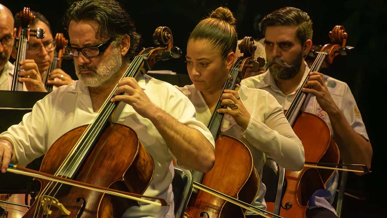 Tres músicos interpretando en el violonchelo durante el Concierto Especial de Verano de la Orquesta Filarmónica de Acapulco