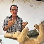 Fotografía de portada del escultor Jorge Alfaro posando junto a su obra en el Fortín Álvarez. El artista posa con su mano real como  está en la escultura con forma de mano humana texturizada con piel de cordero y cicatrices, montada sobre un cubo.