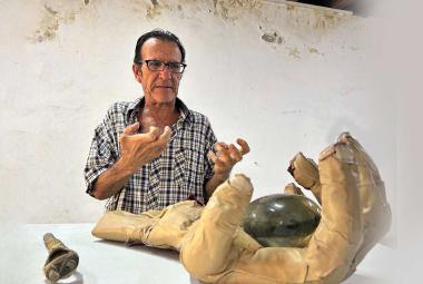 Fotografía de portada del escultor Jorge Alfaro posando junto a su obra en el Fortín Álvarez. El artista posa con su mano real como  está en la escultura con forma de mano humana texturizada con piel de cordero y cicatrices, montada sobre un cubo.