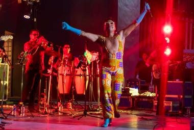 Erik Castrejón se encuentra sobre el escenario del Auditorio del Parque Papagayo de Acapulco con los brazos levantados y un micrófono en una de sus manos, mientras los músicos de su banda permanecen detrás de él durante el concierto homenaje a Juan Gabriel Amor eterno, rolitas de Juanga para mamá.