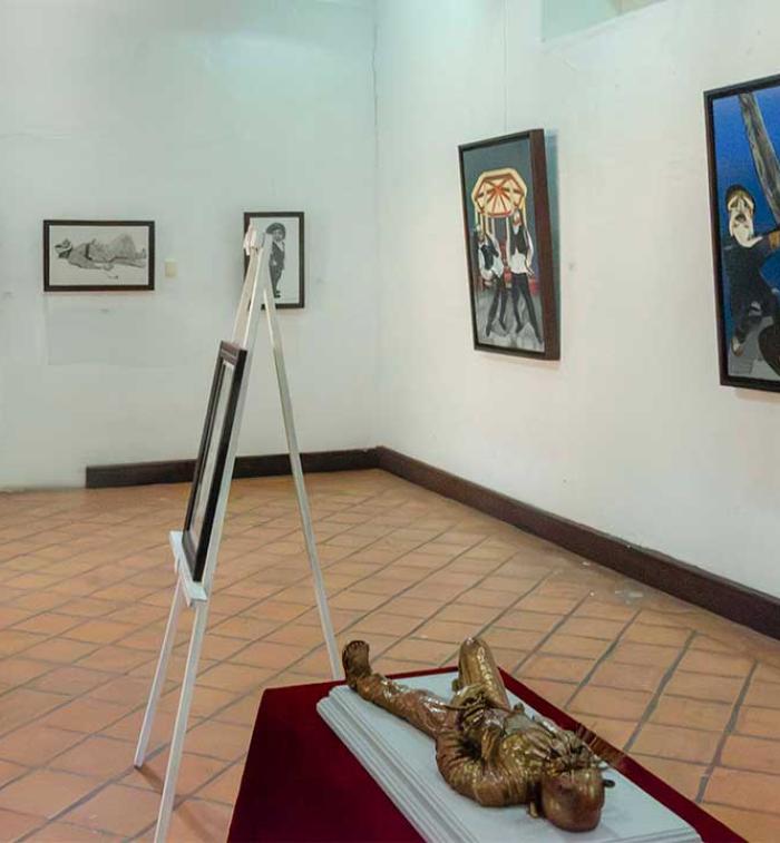 Vista panorámica de la exposición "Orgullo de mis raíces: Copanatoyac" en una sala del Museo Universitario José Juárez. Las pinturas de Miguel Altamirano Velázquez se exhiben en los muros junto con cédulas informativas, mostrando escenas inspiradas en la danza del Tekuanimej y las tradiciones de Copanatoyac, Guerrero.